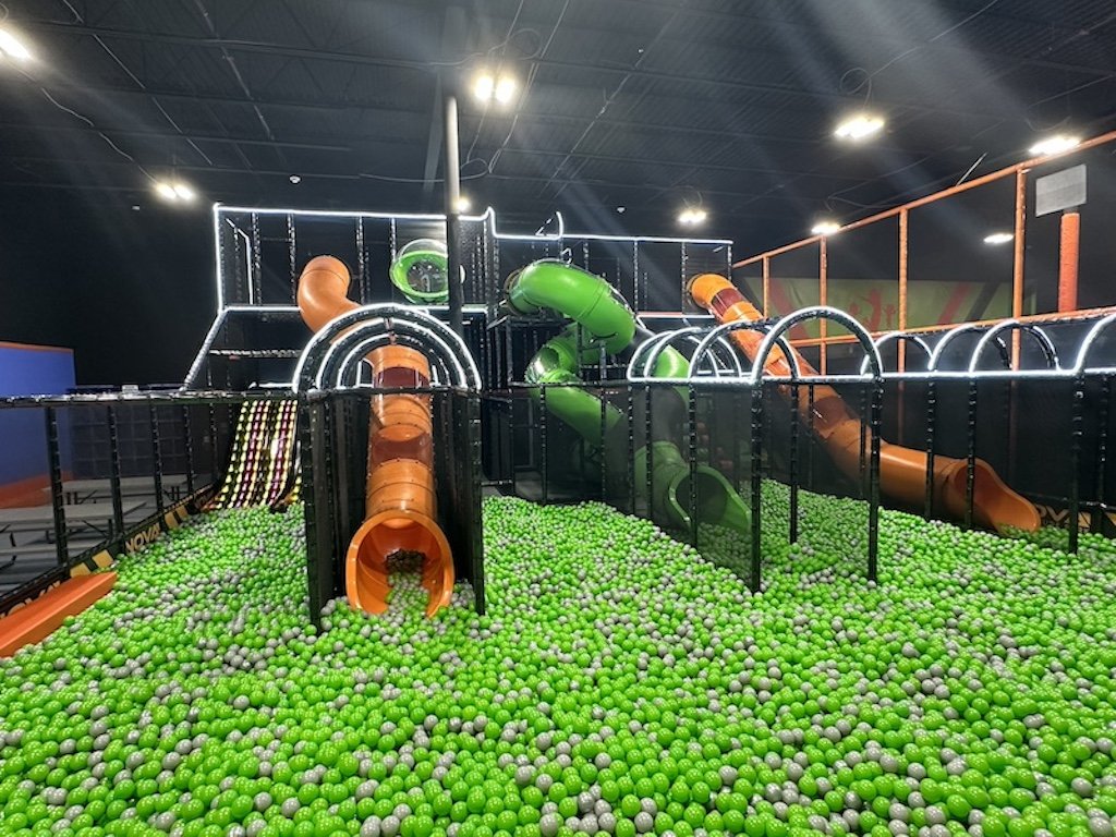 Ball pit and multi-level climbing structure with tube slides at Nova Adventure Park